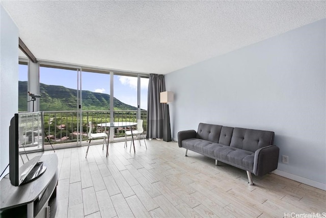 living room with a textured ceiling, light hardwood / wood-style floors, and floor to ceiling windows