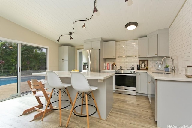 kitchen with a center island, stainless steel appliances, tasteful backsplash, light hardwood / wood-style floors, and sink