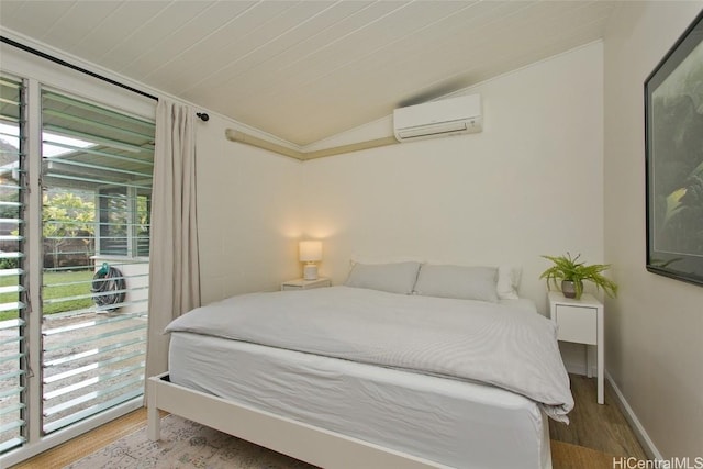 bedroom with hardwood / wood-style flooring, a wall unit AC, and vaulted ceiling