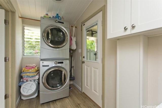 washroom with cabinets, light hardwood / wood-style flooring, stacked washing maching and dryer, and wood ceiling