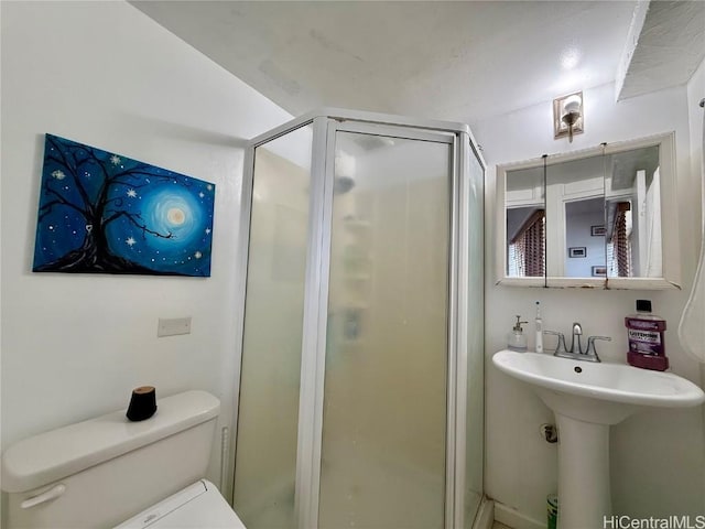 bathroom featuring toilet and a shower with door