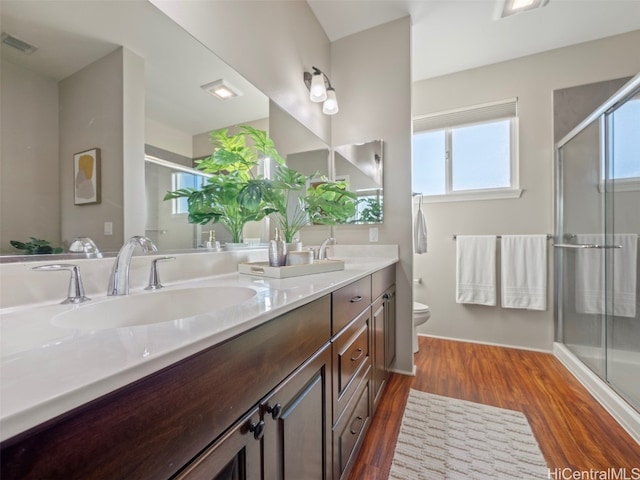 bathroom with toilet, hardwood / wood-style flooring, vanity, and an enclosed shower