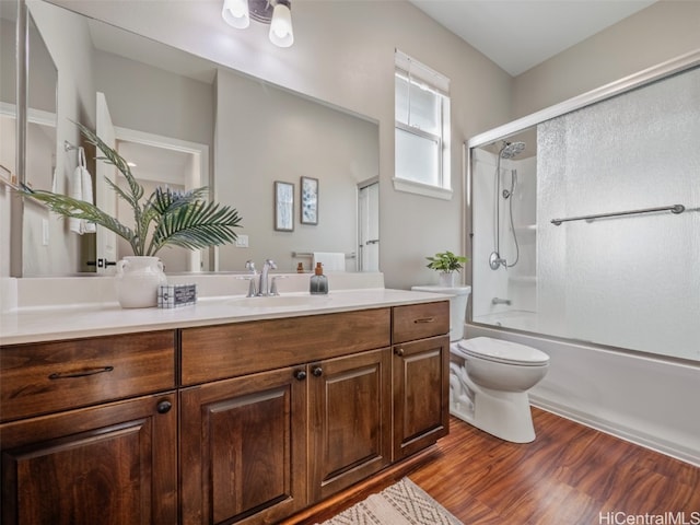 full bathroom featuring toilet, combined bath / shower with glass door, wood-type flooring, and vanity