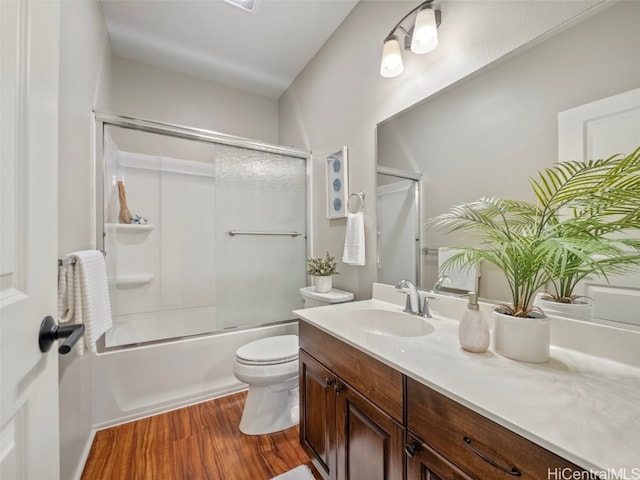 full bathroom with toilet, bath / shower combo with glass door, wood-type flooring, and vanity