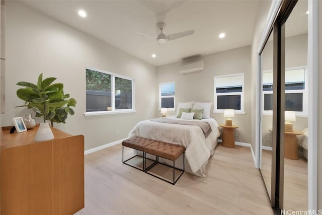 bedroom with ceiling fan, light wood-type flooring, and a wall unit AC