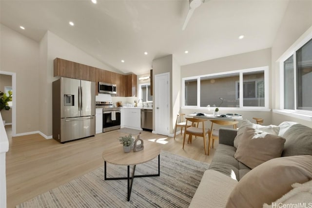 living room with high vaulted ceiling, sink, and light hardwood / wood-style floors