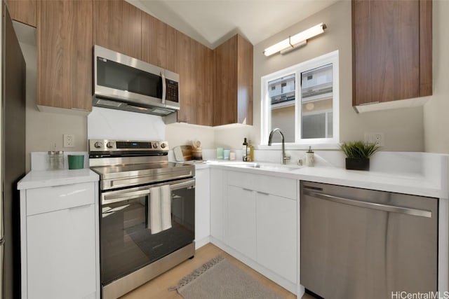 kitchen with appliances with stainless steel finishes, sink, and white cabinetry