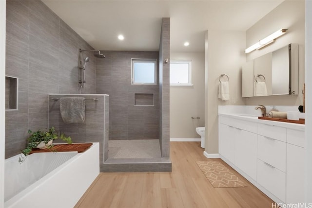 full bathroom with toilet, separate shower and tub, hardwood / wood-style flooring, and vanity