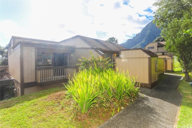 view of side of home with a shed and a mountain view