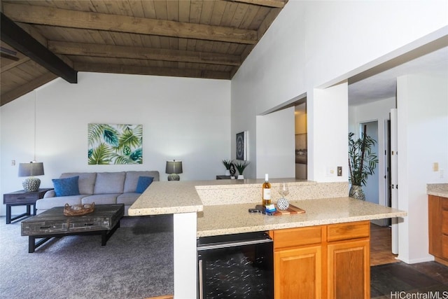 kitchen with vaulted ceiling with beams, light stone counters, kitchen peninsula, wooden ceiling, and beverage cooler