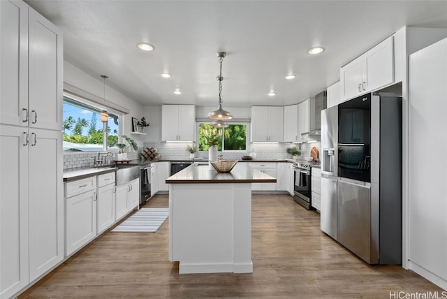 kitchen featuring appliances with stainless steel finishes, white cabinetry, and pendant lighting