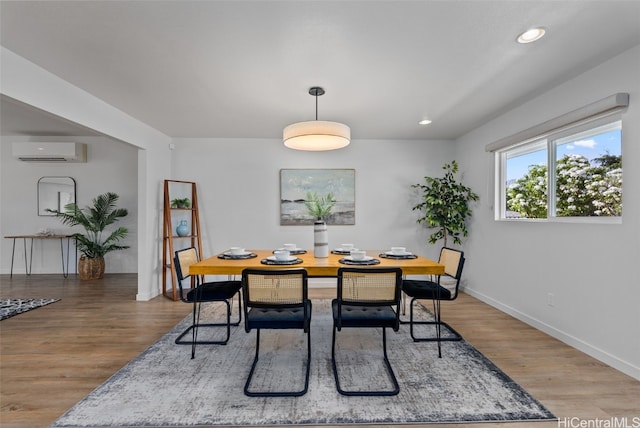 dining space featuring an AC wall unit and hardwood / wood-style flooring