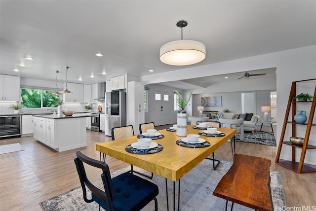 dining room with ceiling fan, sink, beverage cooler, and light hardwood / wood-style flooring