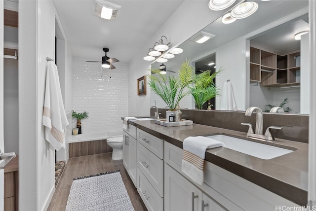 full bathroom featuring toilet, vanity, ceiling fan, hardwood / wood-style floors, and tiled shower / bath combo