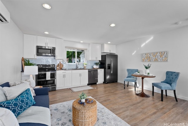 living room with light hardwood / wood-style flooring, an AC wall unit, and sink