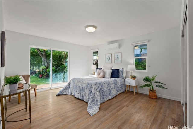 bedroom featuring access to exterior, light hardwood / wood-style flooring, and a wall mounted AC