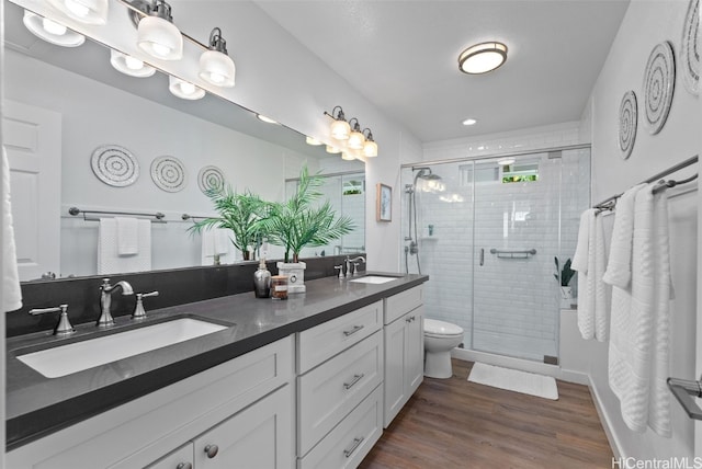 bathroom with toilet, a shower with shower door, hardwood / wood-style floors, and vanity