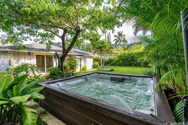 view of pool with a hot tub and a lawn