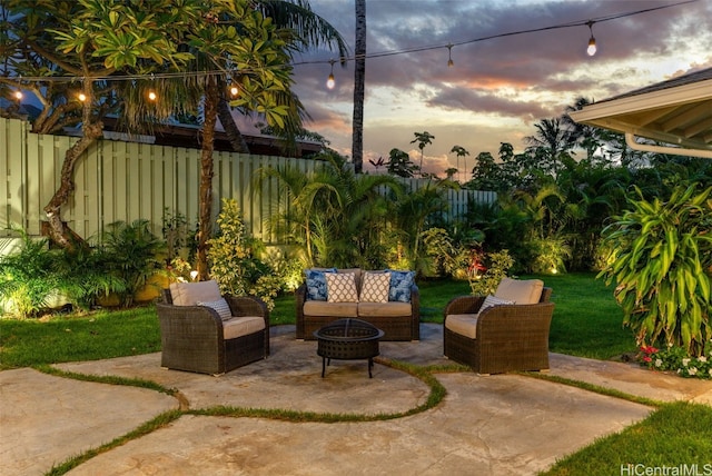 patio terrace at dusk featuring an outdoor living space with a fire pit and a yard