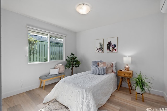 bedroom with light hardwood / wood-style flooring and a wall unit AC