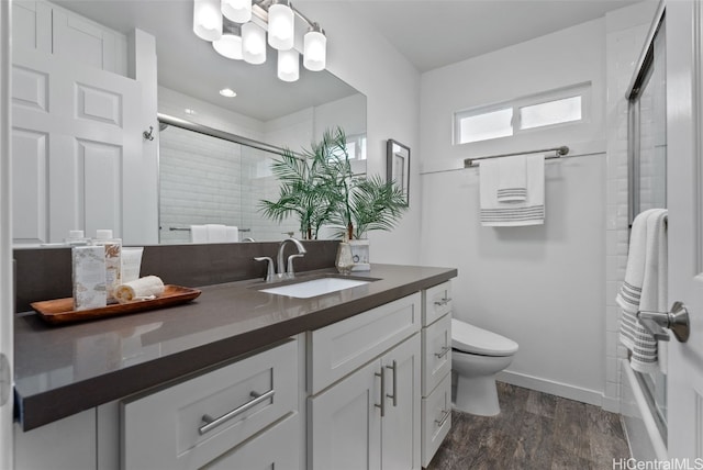 bathroom with toilet, a notable chandelier, wood-type flooring, walk in shower, and vanity