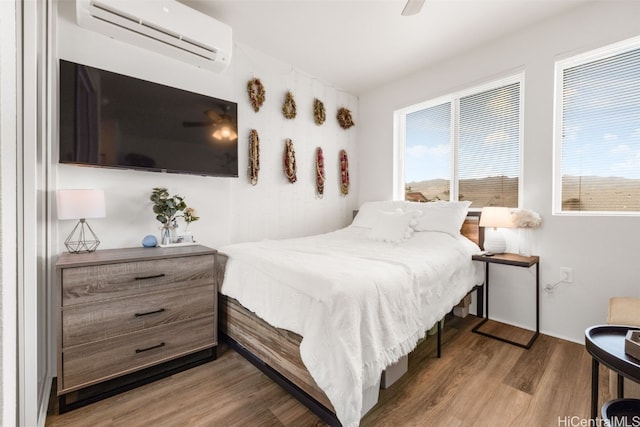 bedroom featuring hardwood / wood-style floors, an AC wall unit, and ceiling fan