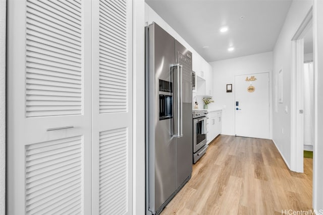 kitchen featuring white cabinets, light wood-type flooring, and premium appliances