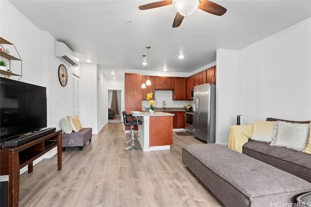 living room featuring sink, light hardwood / wood-style flooring, a wall unit AC, and ceiling fan