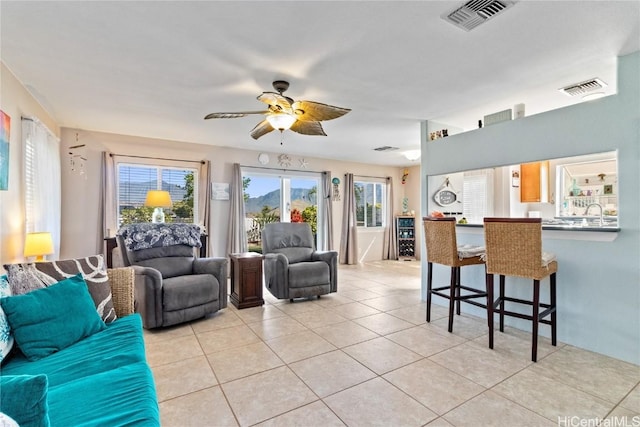 living room with ceiling fan, a wealth of natural light, and light tile patterned floors