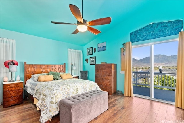 bedroom with ceiling fan, access to exterior, wood-type flooring, a mountain view, and vaulted ceiling