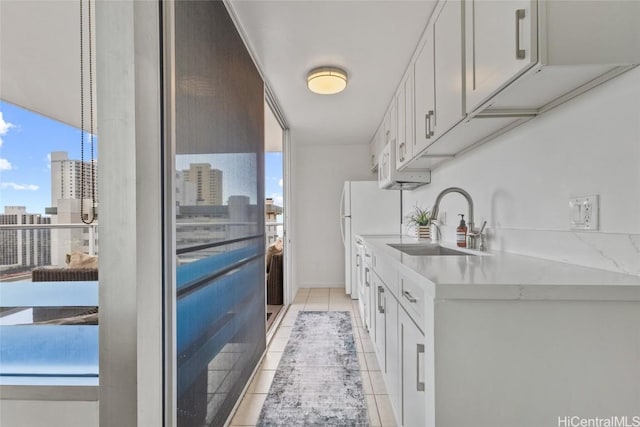 kitchen with light tile patterned floors, white cabinets, and sink