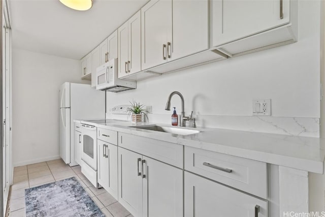 kitchen with white appliances, white cabinetry, sink, light tile patterned flooring, and light stone counters