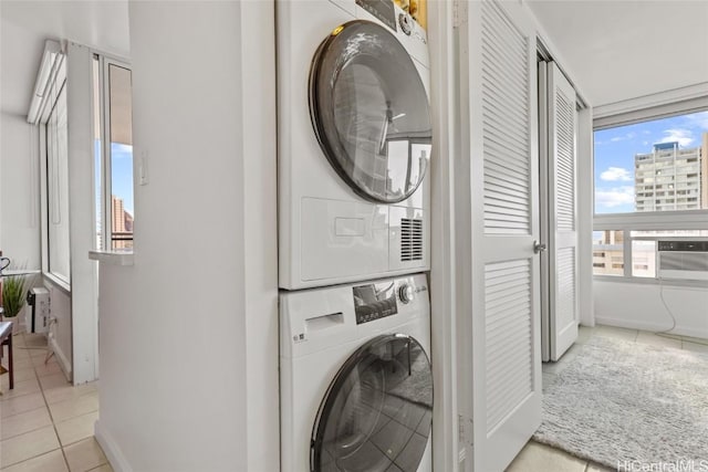 laundry area with stacked washing maching and dryer and light tile patterned flooring