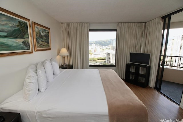 bedroom with hardwood / wood-style flooring and multiple windows