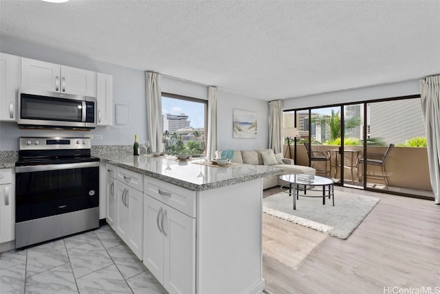 kitchen with stainless steel appliances, a healthy amount of sunlight, white cabinets, and kitchen peninsula