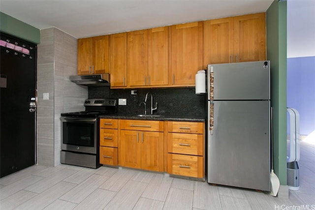 kitchen with appliances with stainless steel finishes, dark stone countertops, backsplash, and sink