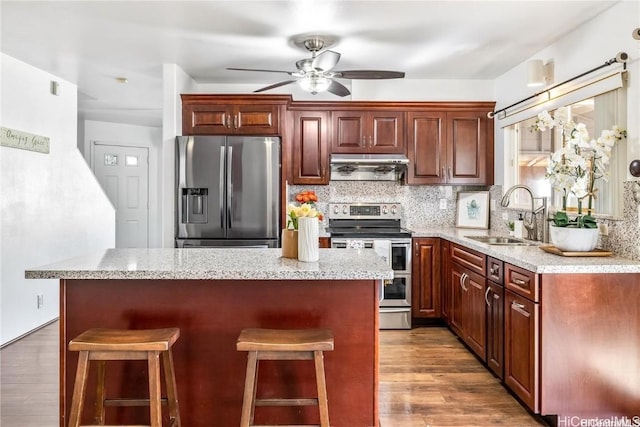 kitchen featuring sink, appliances with stainless steel finishes, exhaust hood, and a kitchen island