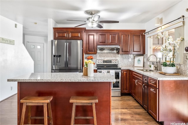 91-219 Naina Pl, Ewa Beach, HI 96706 - kitchen with stainless steel appliances, range hood, ceiling fan, wood finished floors, and a breakfast bar area