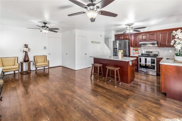 kitchen with a center island, decorative backsplash, a kitchen breakfast bar, dark wood-type flooring, and stainless steel appliances