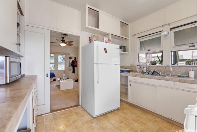 kitchen with white refrigerator, range, sink, and white cabinets