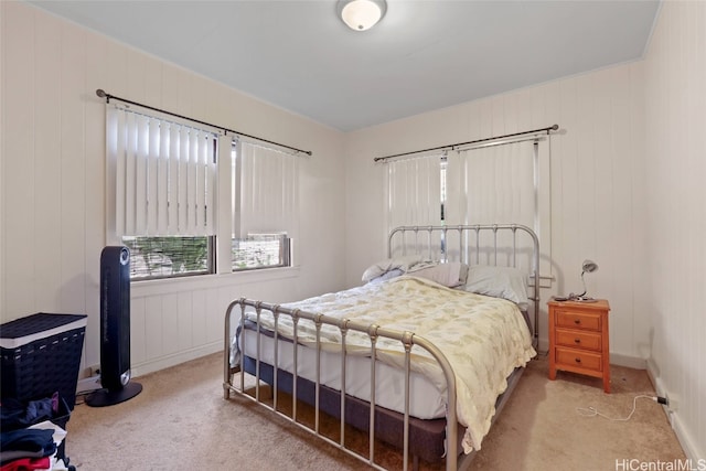 bedroom with light colored carpet and wooden walls