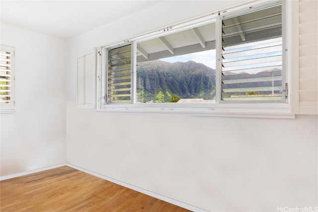 empty room with a mountain view and hardwood / wood-style floors