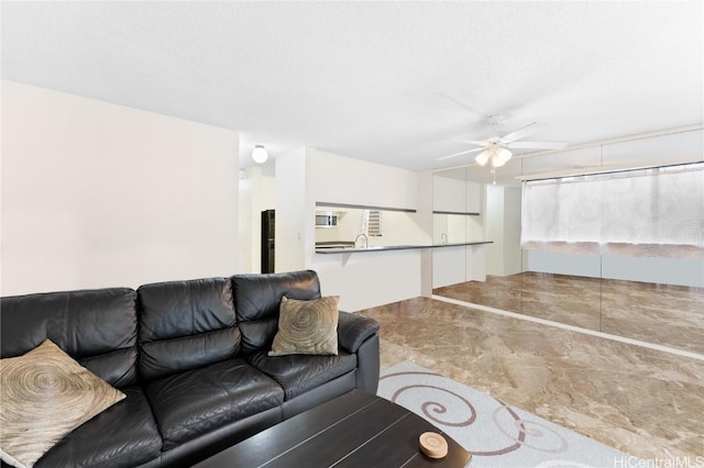 living room featuring ceiling fan, sink, and a textured ceiling