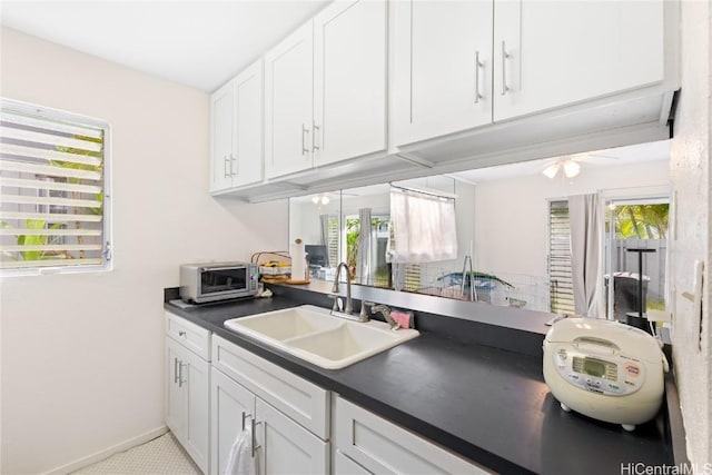 kitchen featuring a healthy amount of sunlight, sink, and white cabinets