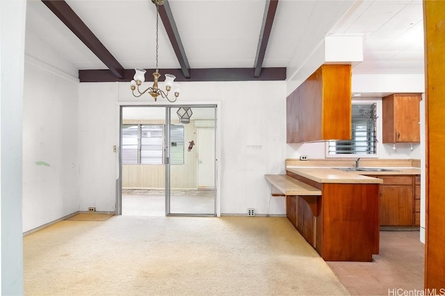 kitchen featuring beamed ceiling, a notable chandelier, sink, and pendant lighting