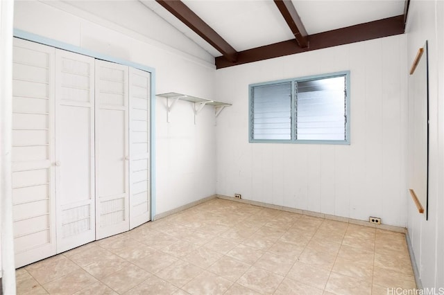 unfurnished bedroom with lofted ceiling with beams and a closet