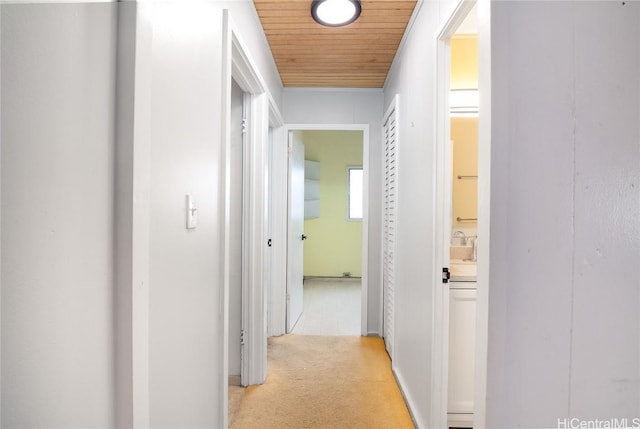 hallway featuring light carpet and wooden ceiling