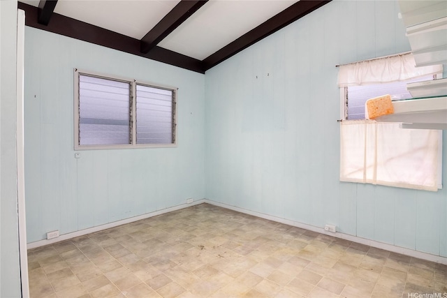 unfurnished room with tile patterned floors and beam ceiling