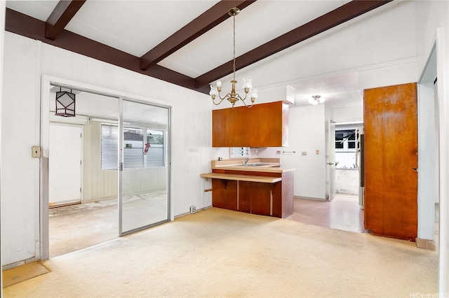 kitchen with an inviting chandelier, pendant lighting, lofted ceiling with beams, brown cabinets, and a sink