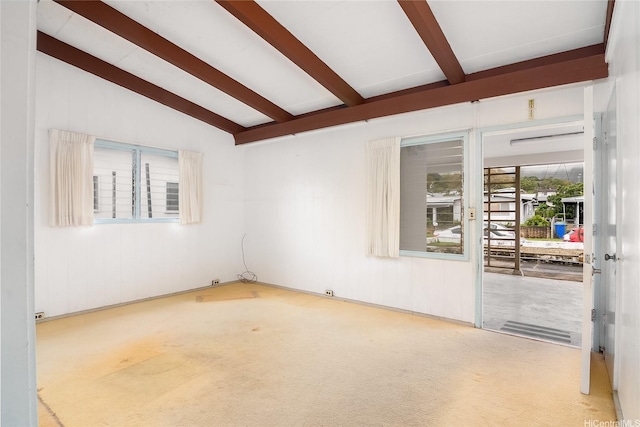 empty room with carpet floors and lofted ceiling with beams